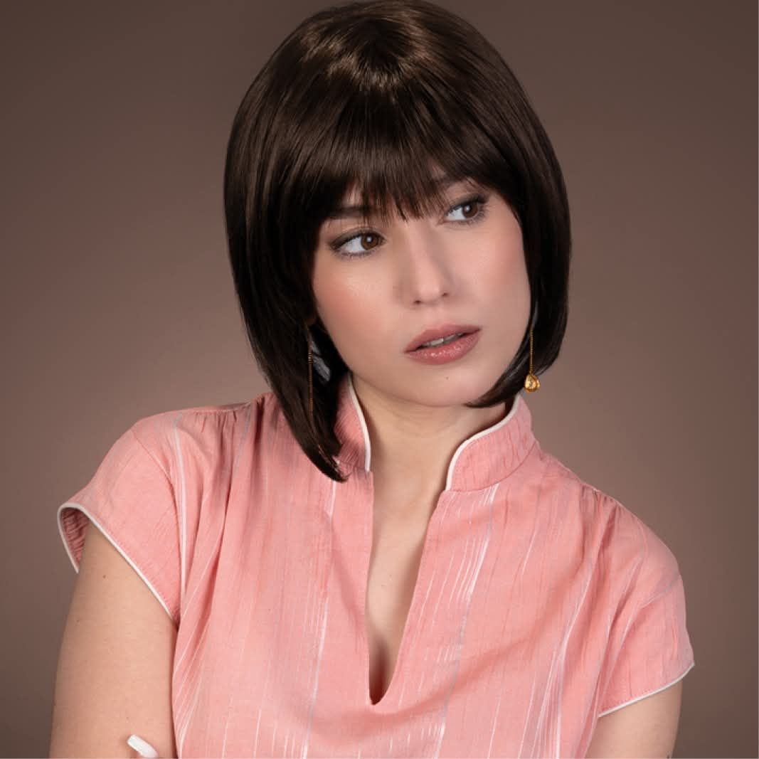 La femme porte une chemise rose et une perruque