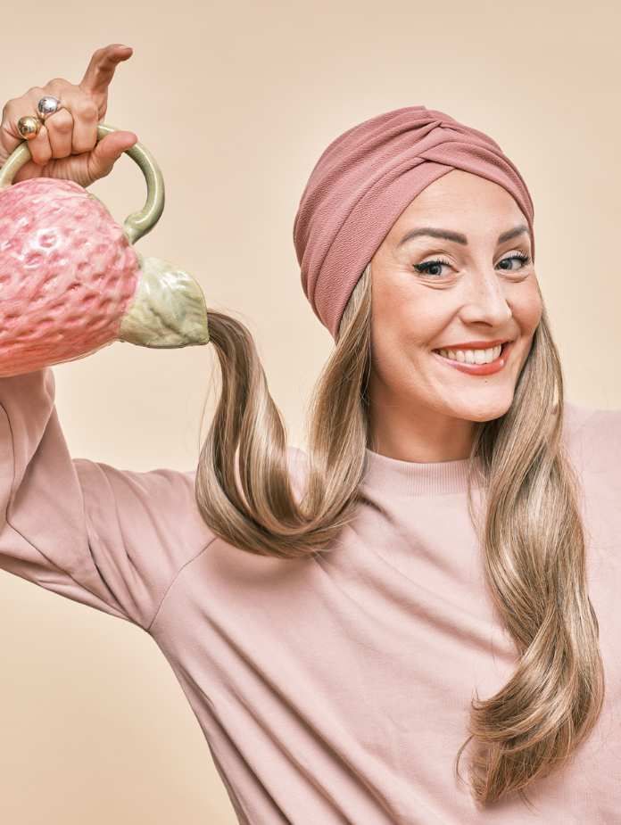 Une femme portant un turban tient une théière dans sa main.