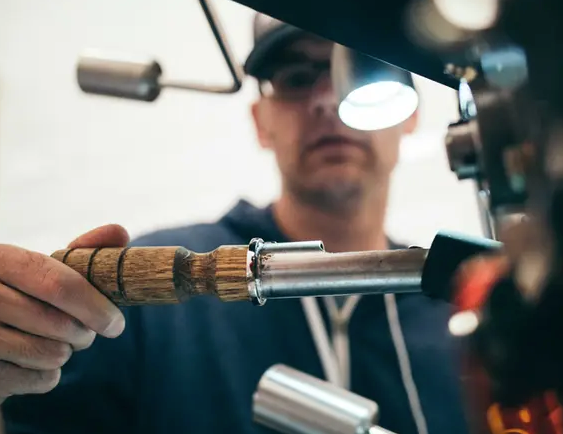 A man is working on a machine with a wooden handle.