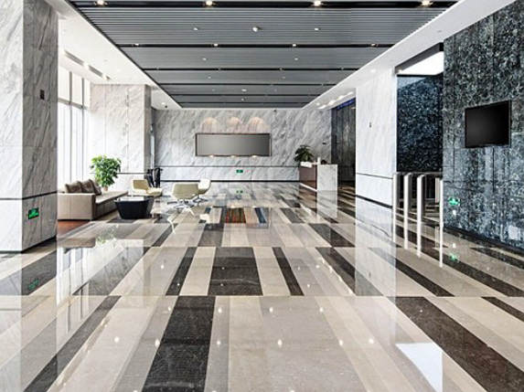 A large lobby with a marble floor and a television on the wall.