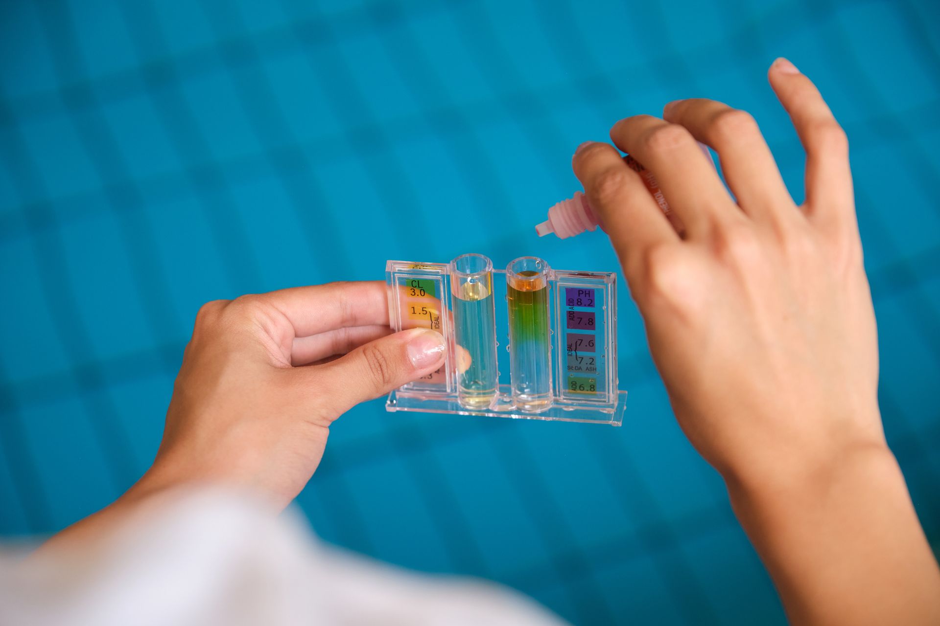 A technician adding reagent to test tubes for chlorine and ph control in a swimming pool. 
