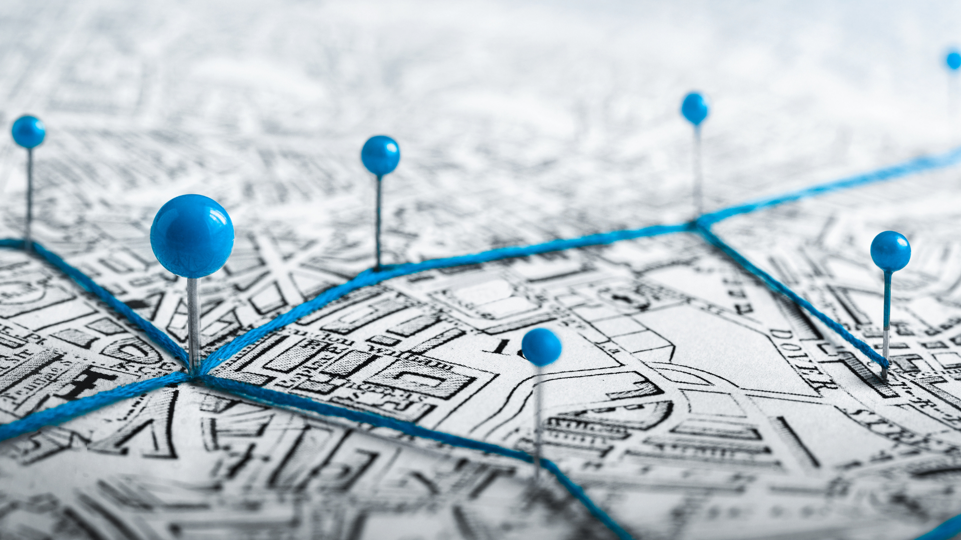 Blue map pins marking locations on a folded city map with a highlighted route