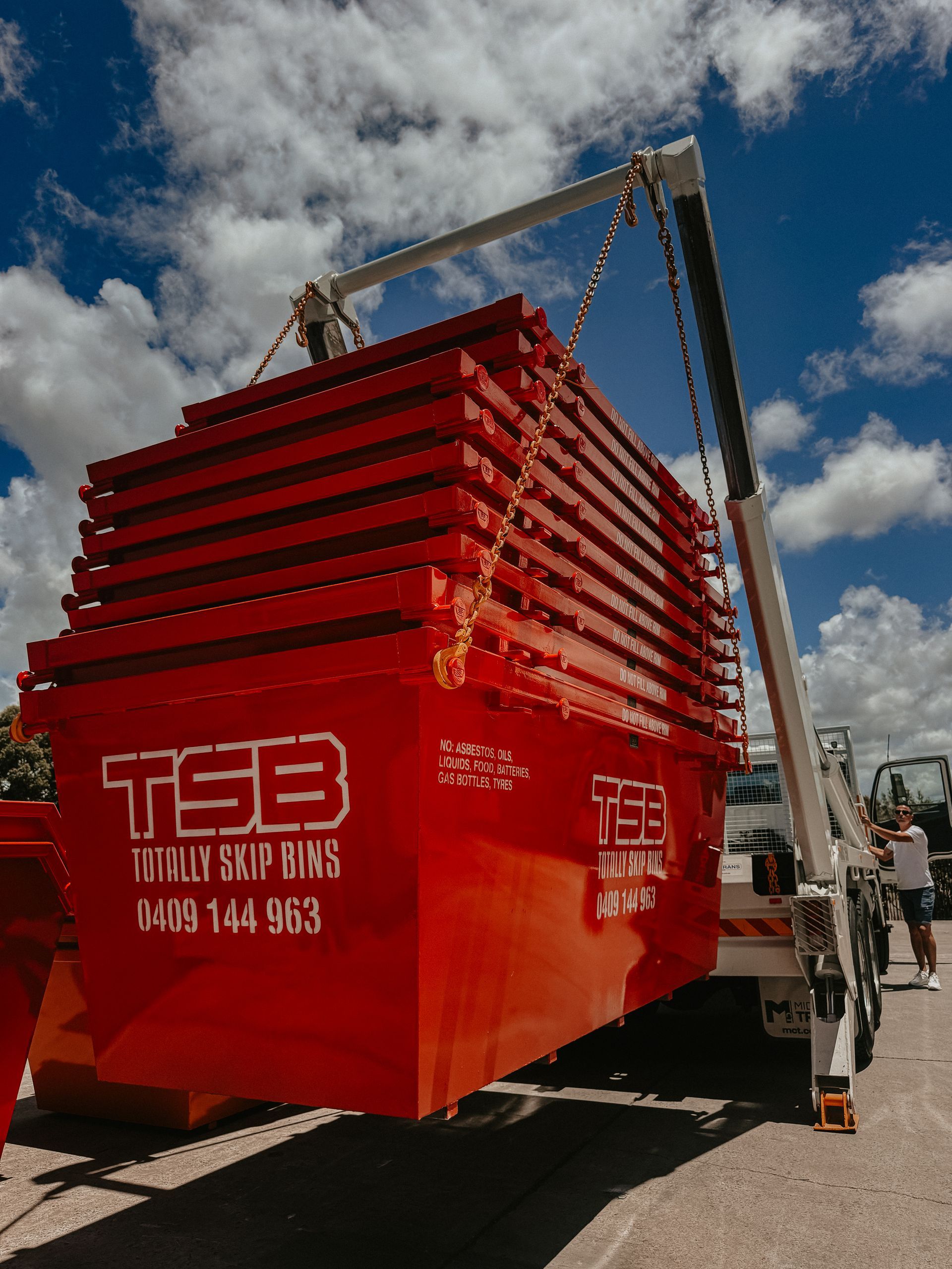 A Red Dumpster is Being Loaded Onto a Truck — Totally Skip Bins in Palen Creek, QLD