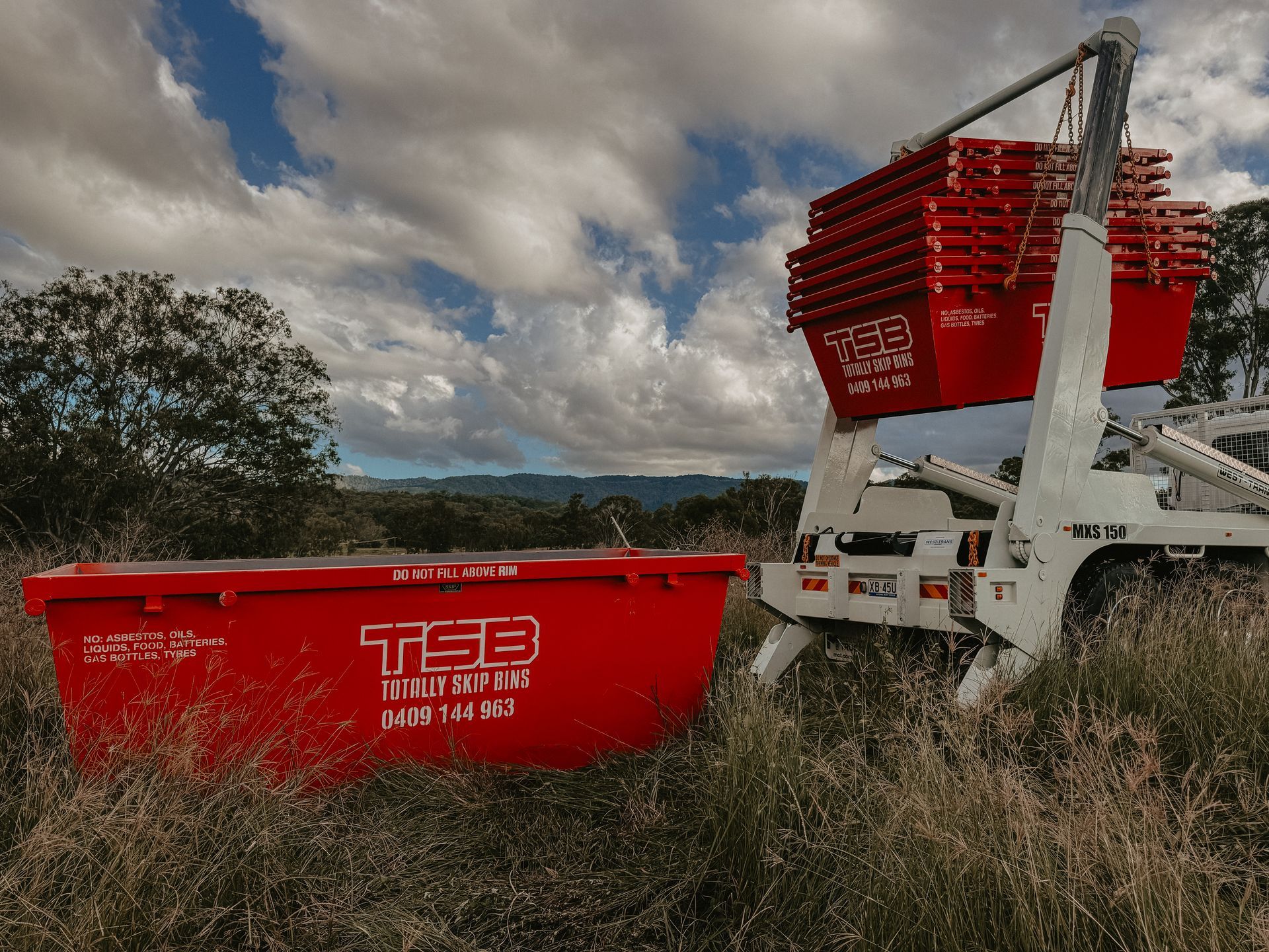 Red Skip Bins Placed in a Grassy Field