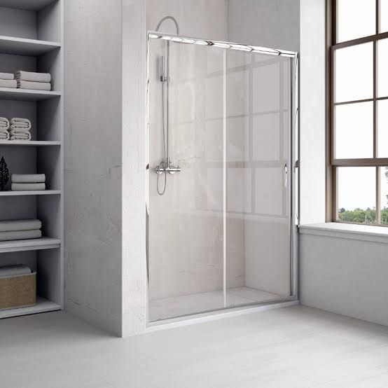 Ducha moderna a ras de suelo con mampara de cristal transparente en un baño luminoso.