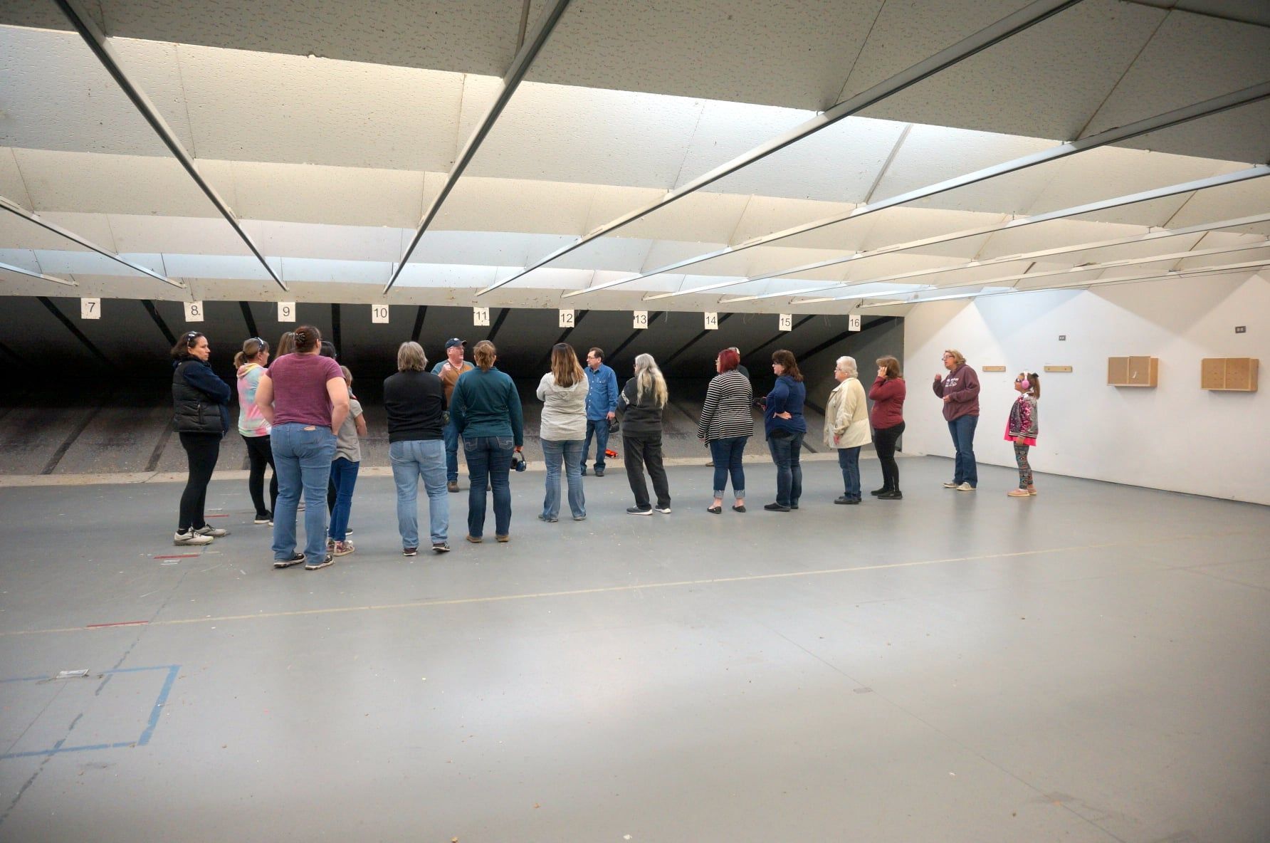 A group of people are standing in a circle in an empty room.