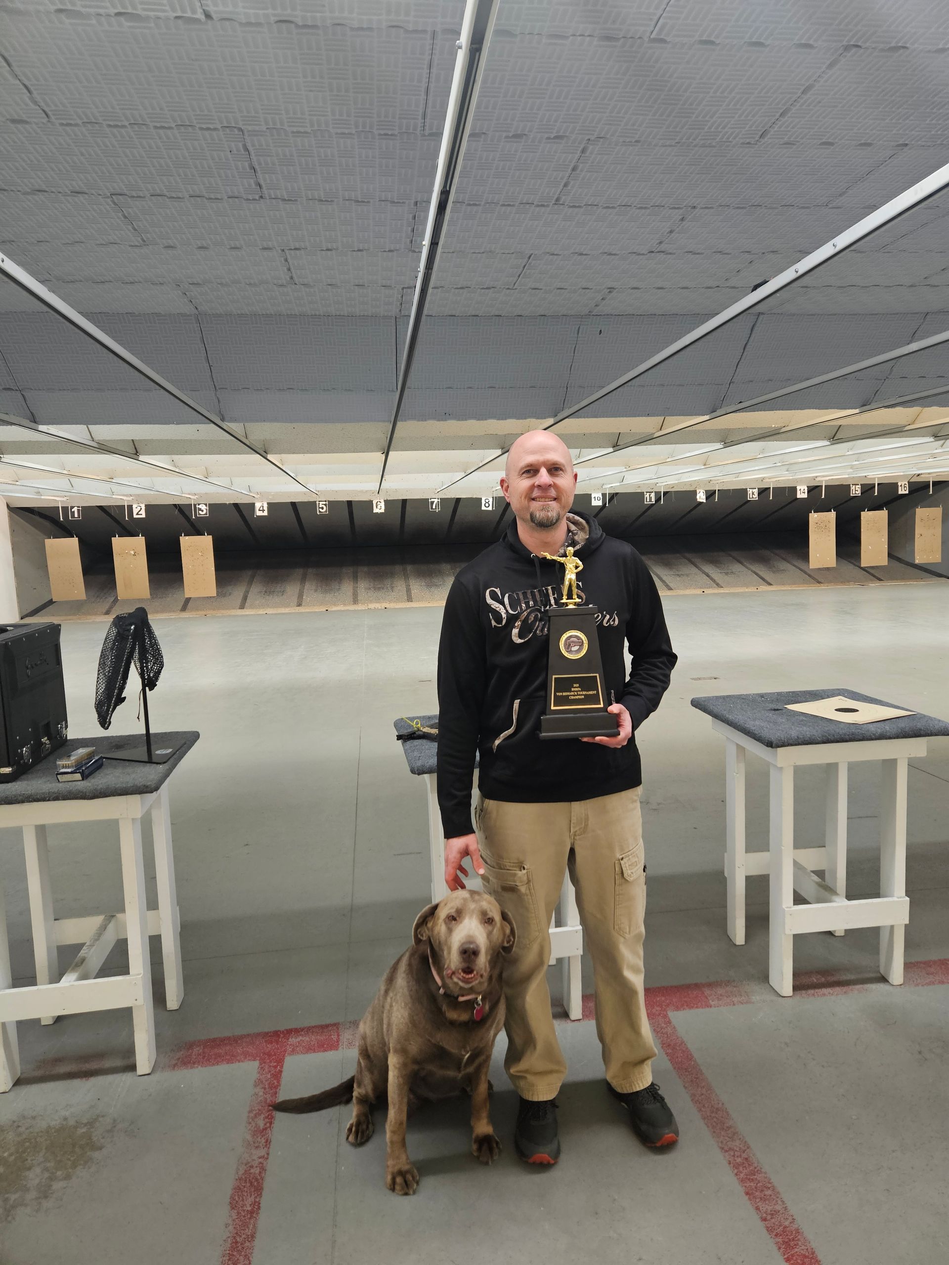 A man standing next to a dog holding a trophy