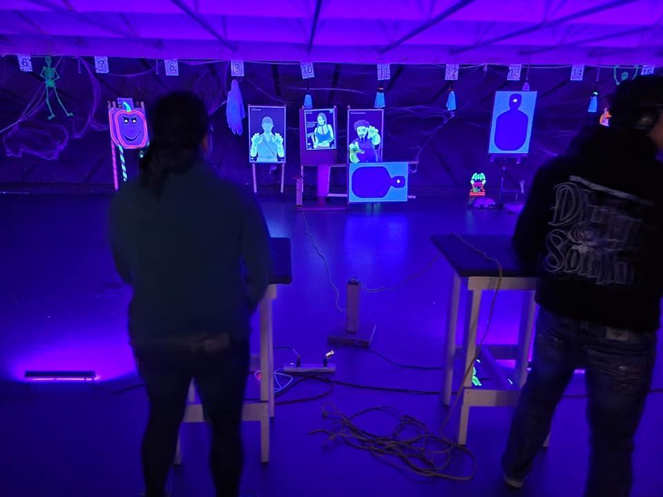 Two people are standing in a dark room with purple lights.