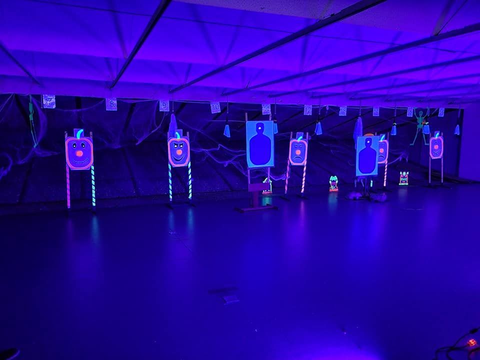 Shooting range with targets illuminated by purple light.