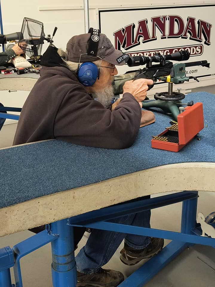 Man with beard and ear protection shoots rifle at a Mandan Sporting Goods range.