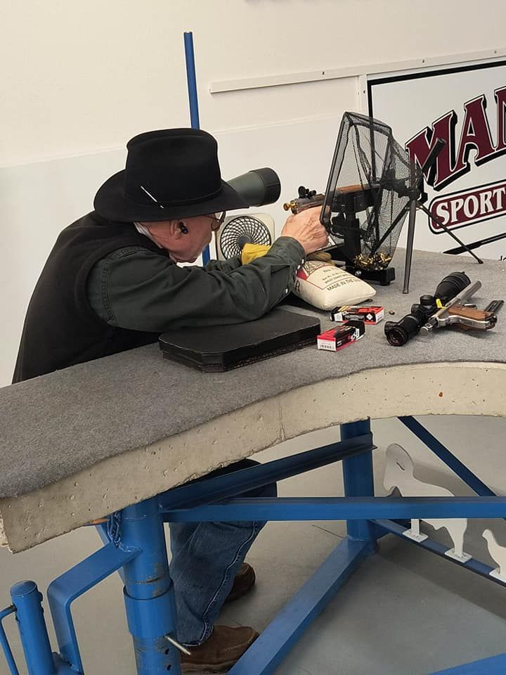 A man in a cowboy hat is sitting at a table in front of a sign that says mad sport