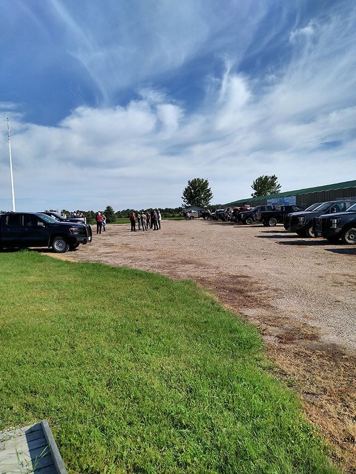 A row of trucks are parked in a dirt lot.