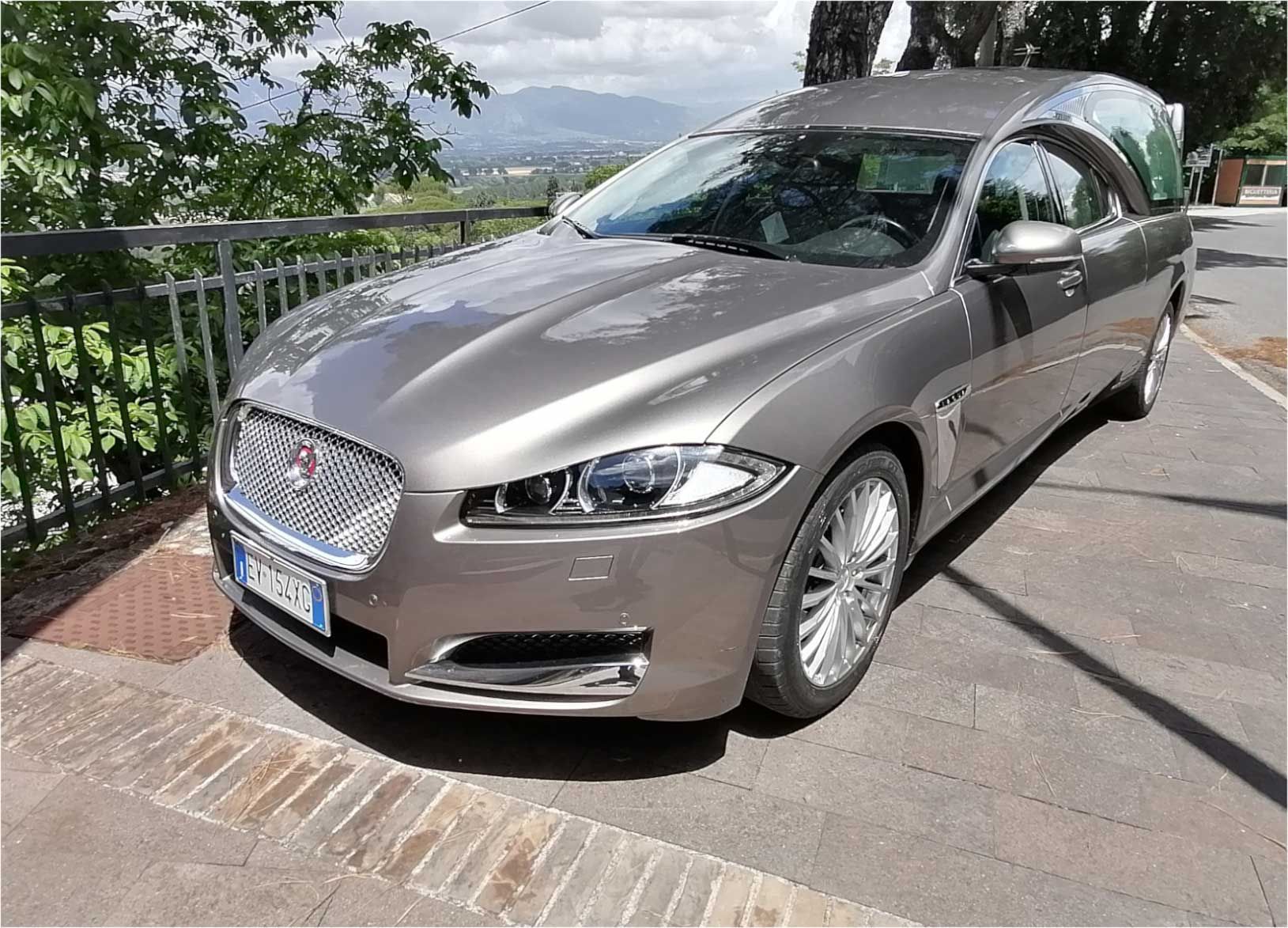Berlina argentata parcheggiata su un punto panoramico con montagne sullo sfondo.