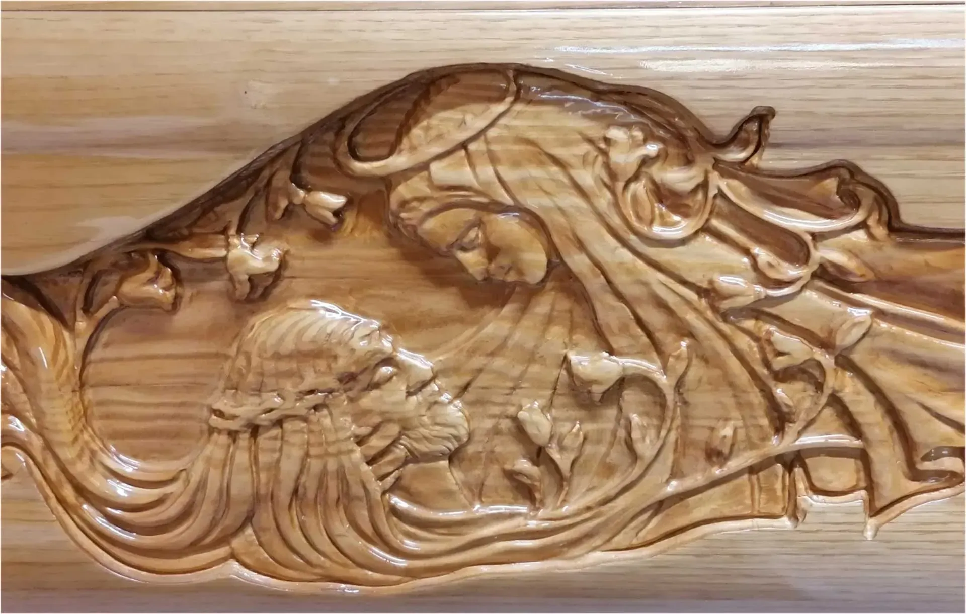 Rilievo in legno intagliato raffigurante una creatura marina mitologica su un pannello di legno chiaro.