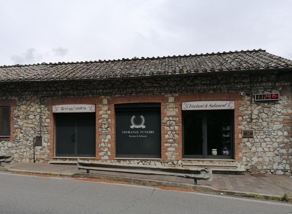 Negozio con facciata in pietra, vetrine scure e insegna sopra l'ingresso, in una strada tranquilla.