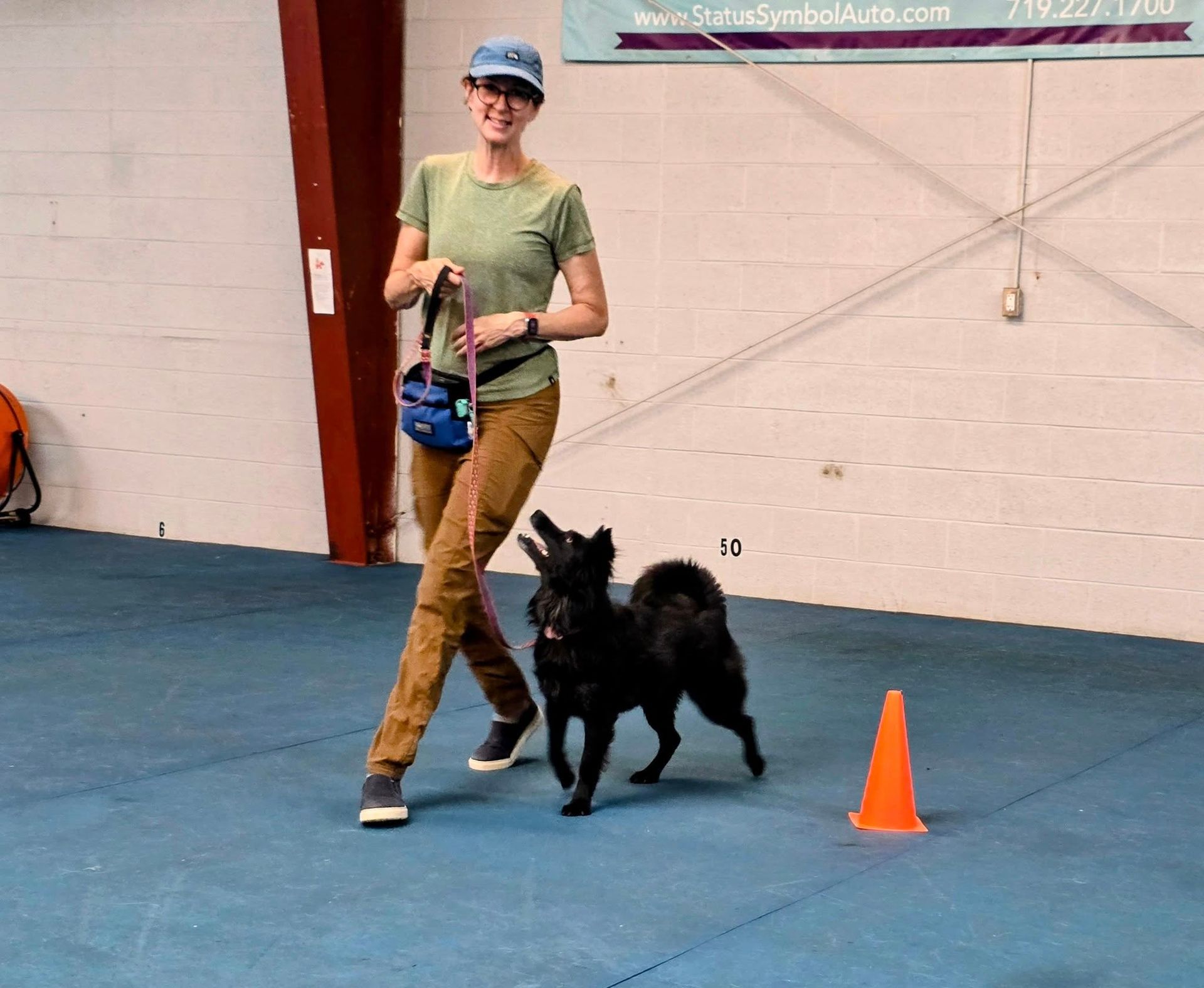 A rescue dog heeler mix and her baseball hat clad mom practice Rally Obedience.
