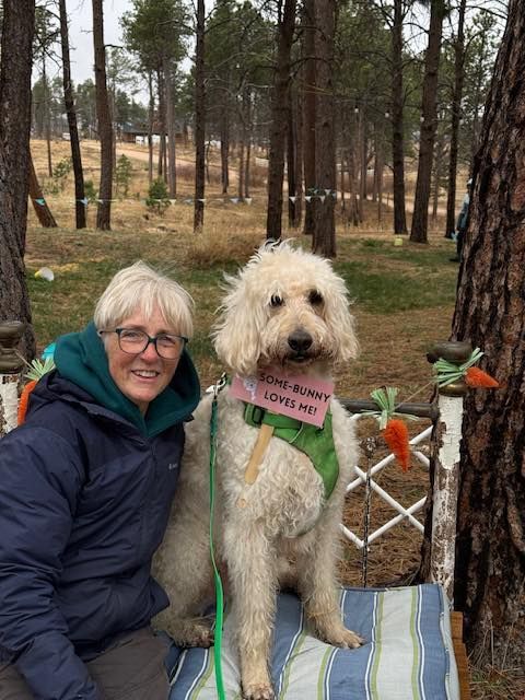 A doodle and his person pose in the woods