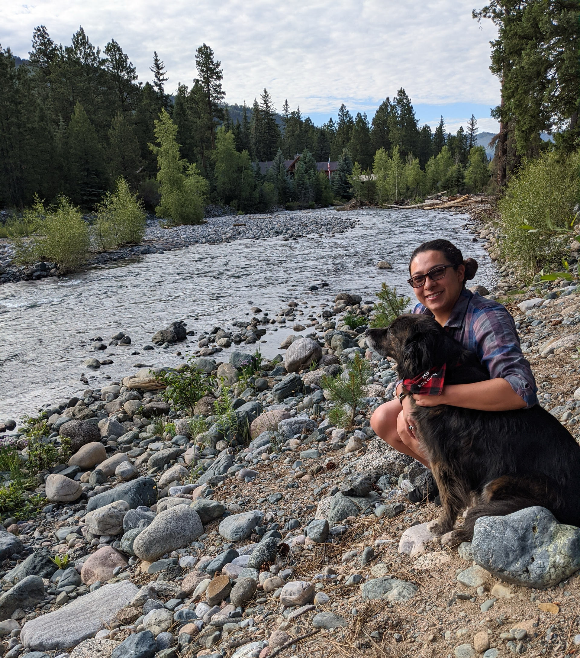 A young woman and her rescue dog on the bank of a river