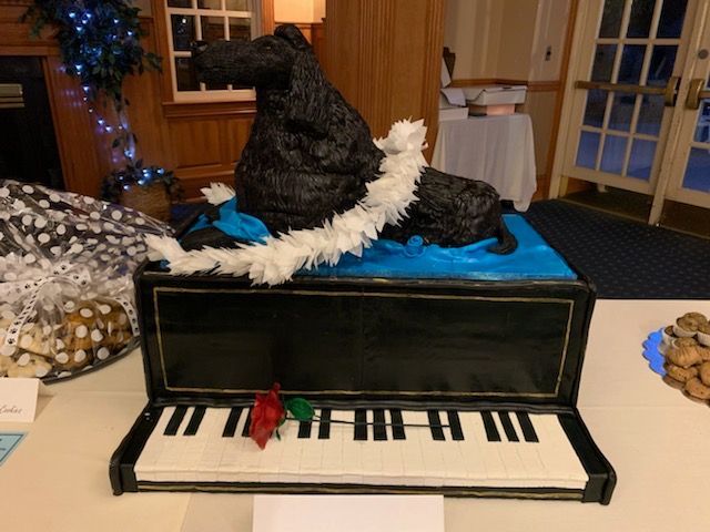 An ornate cake - a dog sitting atop a piano