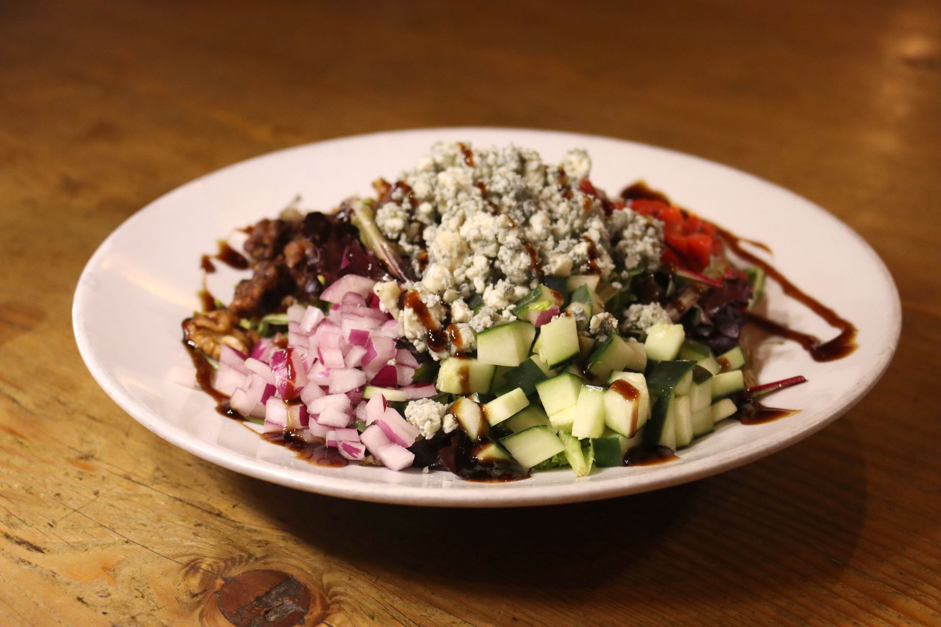 A white plate topped with a salad of onions and cucumbers on a wooden table.