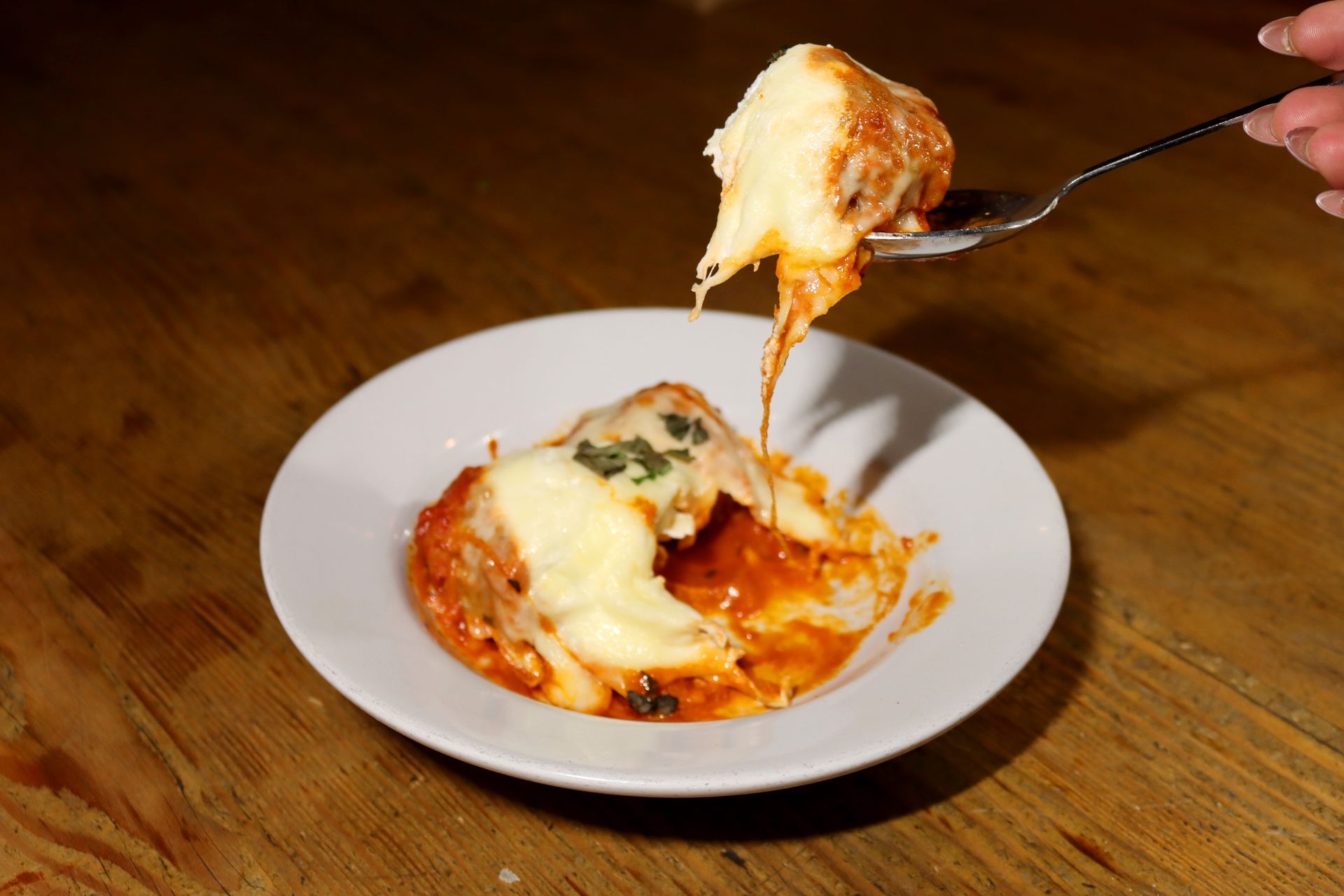 A person is holding a spoon over a plate of food.