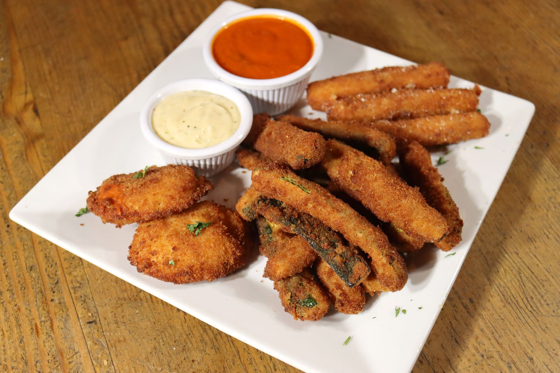 A white plate topped with fried food and dipping sauces on a wooden table.