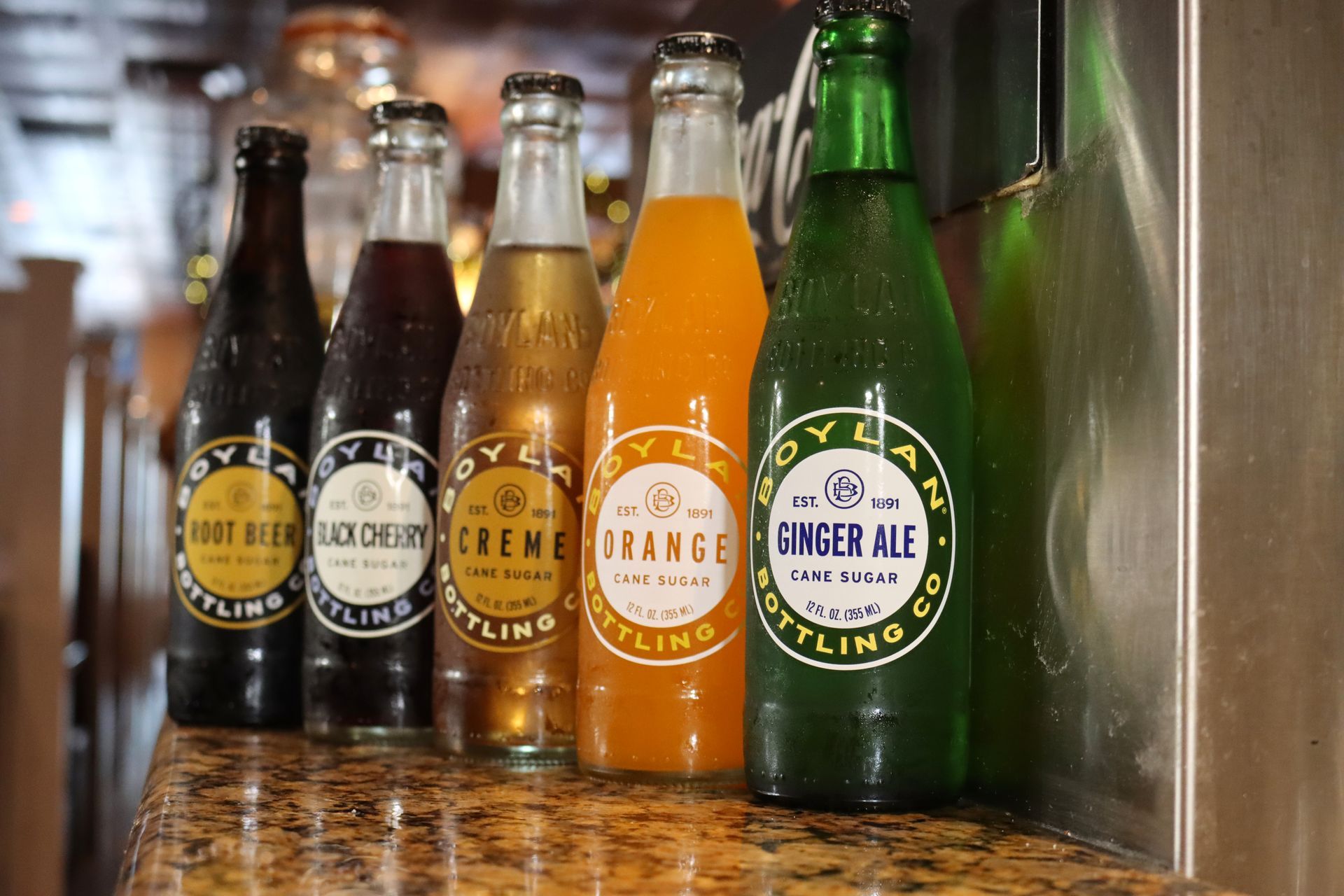Several bottles of soda are lined up on a counter including ginger ale