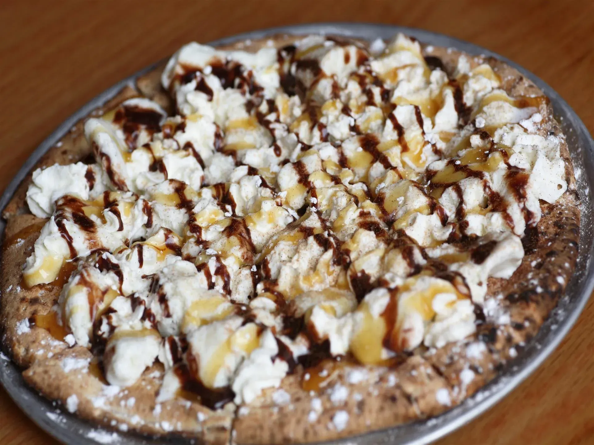 A pizza with a lot of toppings on it is on a plate on a table.
