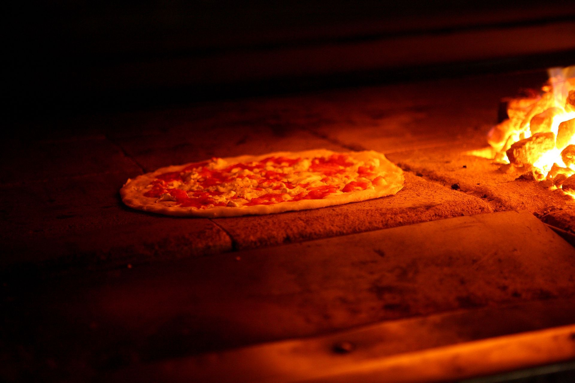 A pizza is being cooked in an oven with flames coming out of it.