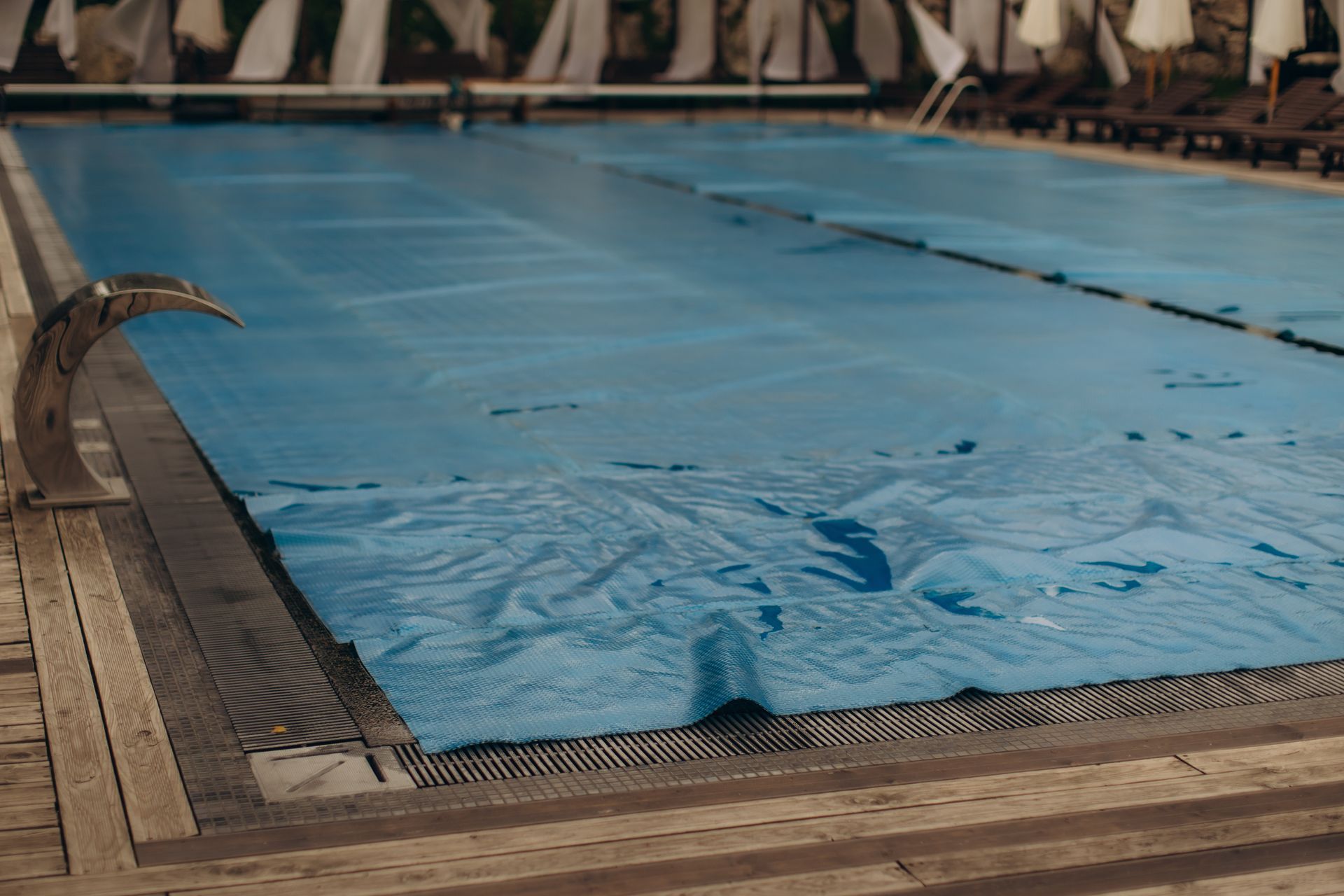 Covered indoor swimming pool with a blue safety cover and lane lines visible at the edge