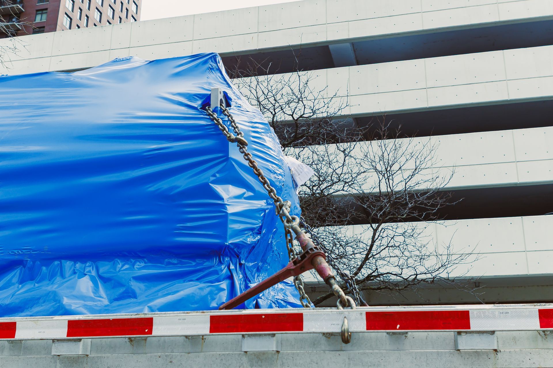 Blue tarp covering a damaged structure beside a curb in front of a building Blue tarp covering a damaged structure beside a curb in front of a building