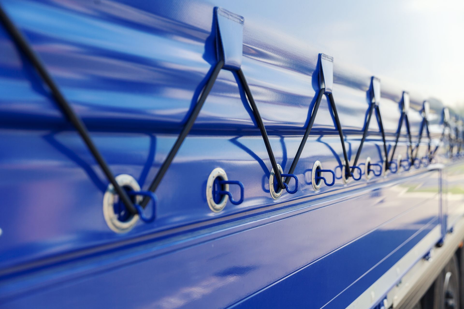 Blue truck side with tied-down tarp and bungee cords in close-up