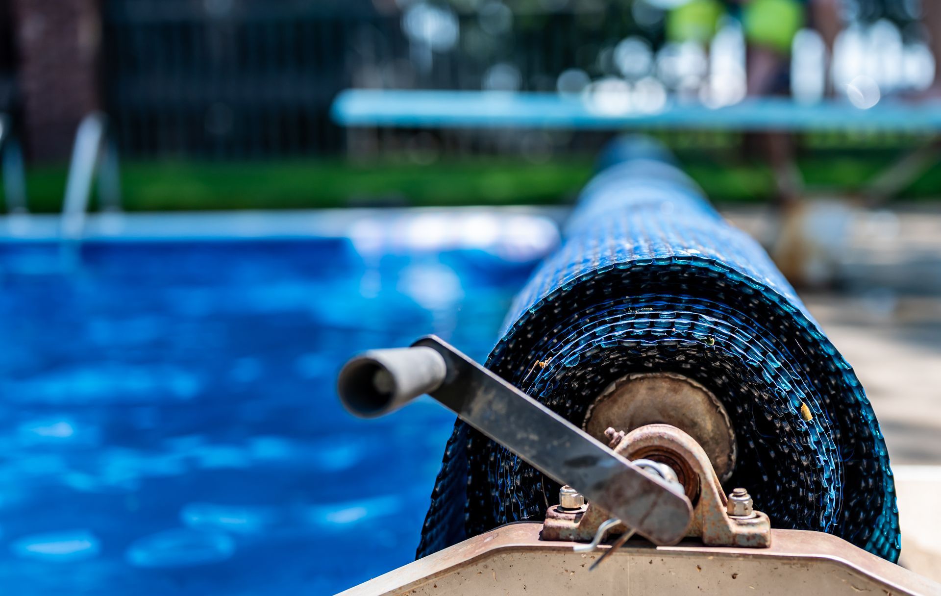 Pool vacuum hose on a reel beside a blue swimming pool