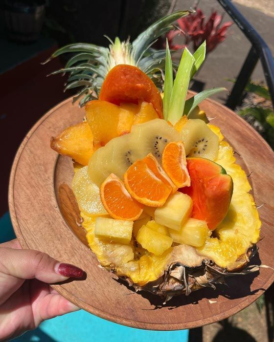 A person is holding a pineapple filled with fruit