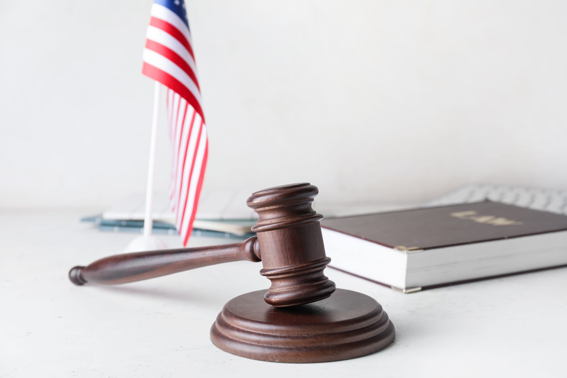 Judge’s gavel on a desk beside a small American flag and law book