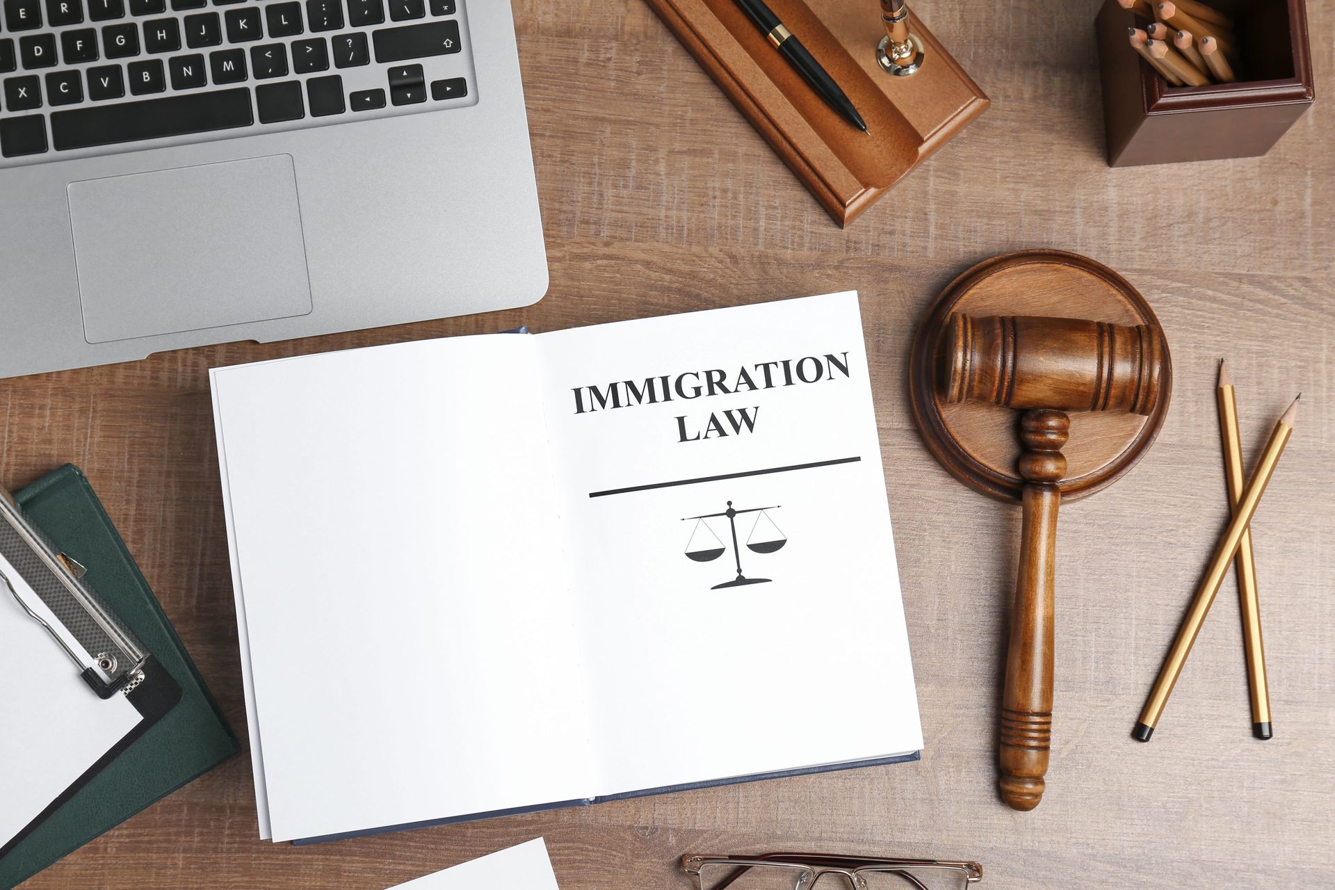 Immigration law book on desk with gavel, laptop, and scales of justice