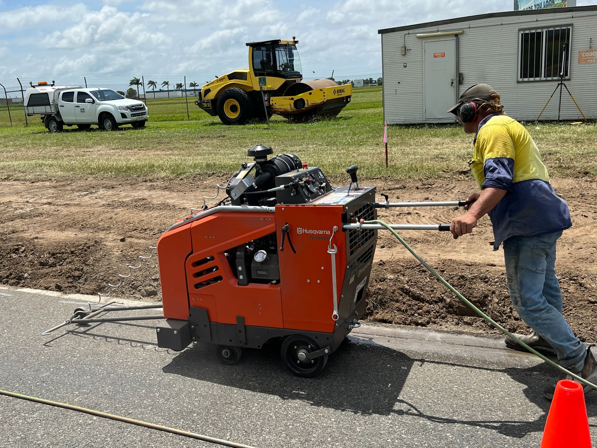 Person operating road saw cutting asphalt; construction site— Ablecut Concrete Cutting & Coring In Marian, QLD