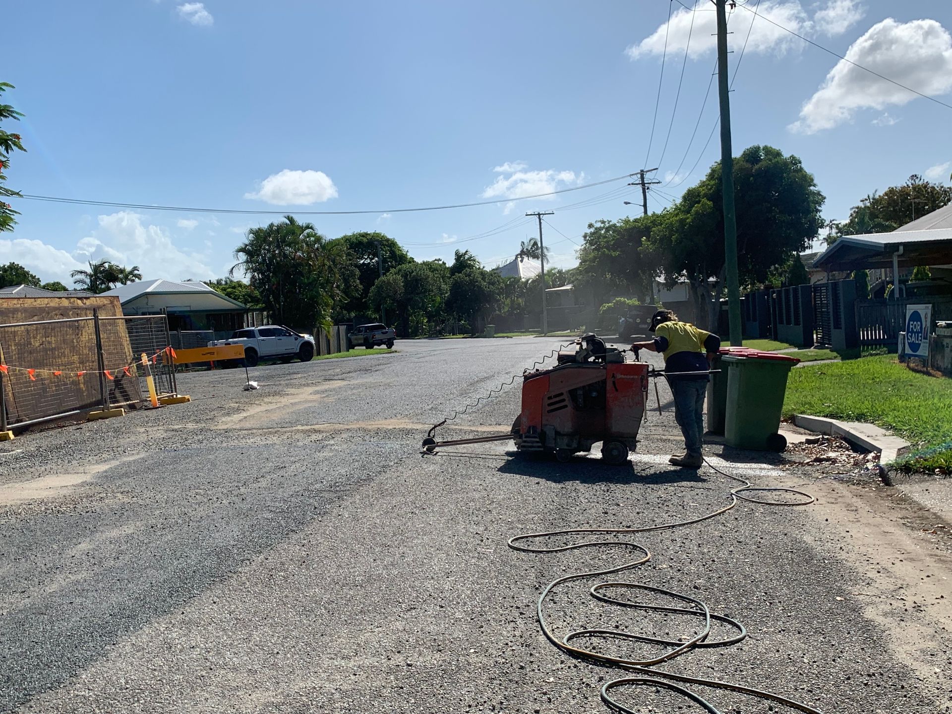 Dusty road with construction barrels, trash bins, and a street sweeper under a bright blue sky. — Ablecut Concrete Cutting & Coring In East Mackay, QLD