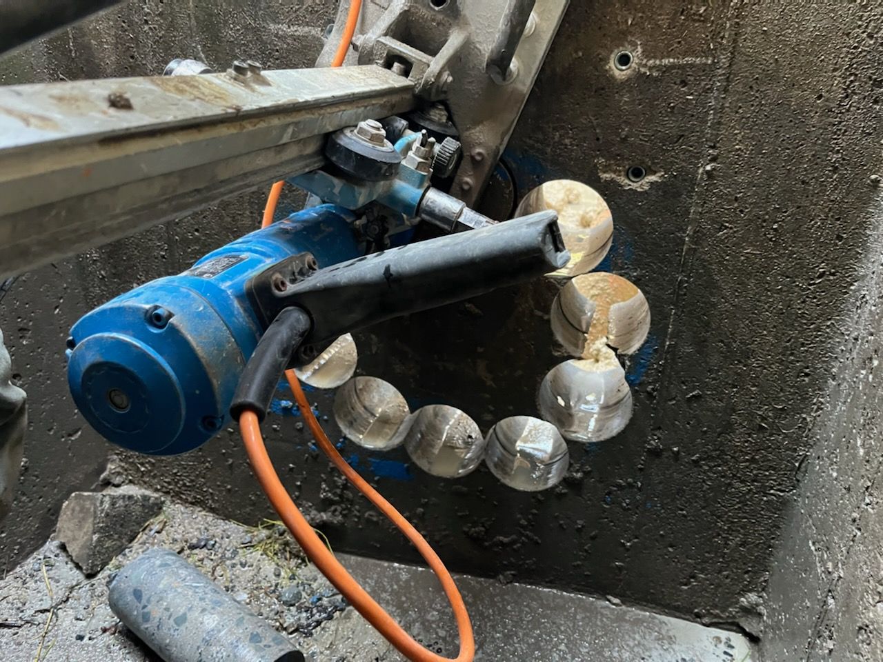 Blue industrial robotic arm assembling a circular ring of clear bulbs with orange cables — Ablecut Concrete Cutting & Coring In East Mackay, QLD