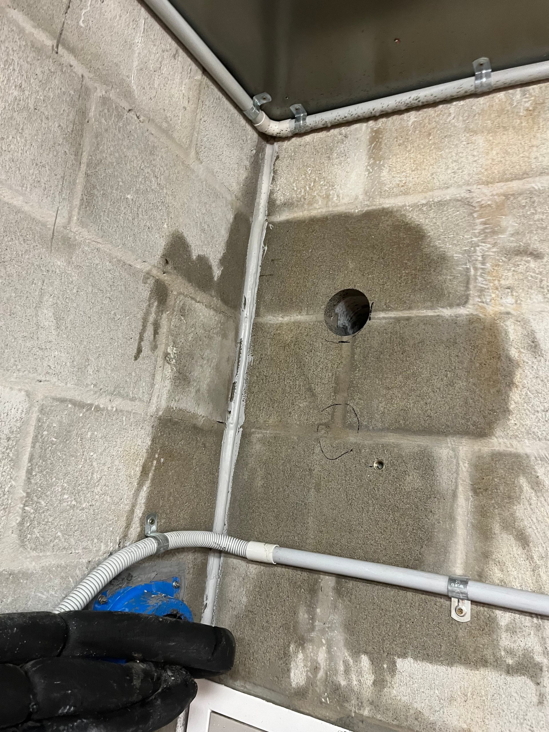 Wet concrete wall corner with white pipes and a black-gloved hand holding a blue cloth — Ablecut Concrete Cutting & Coring In East Mackay, QLD