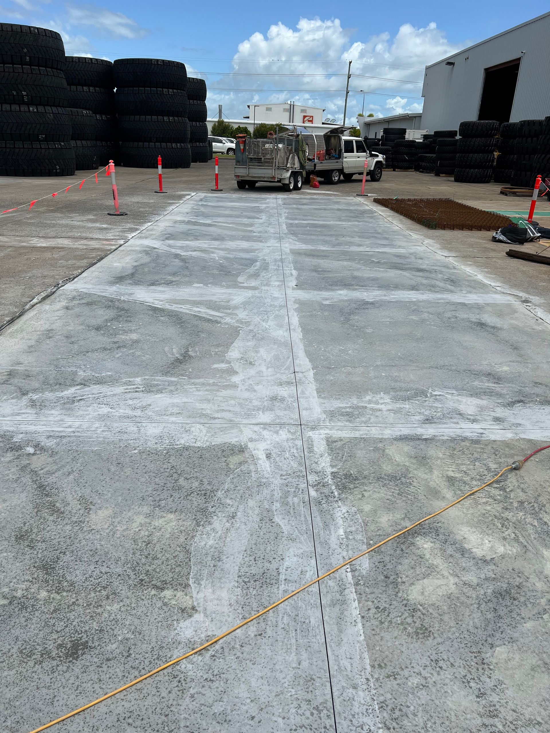 Concrete saw on concrete surface; cement truck and cloudy sky in background— Ablecut Concrete Cutting & Coring In Marian, QLD