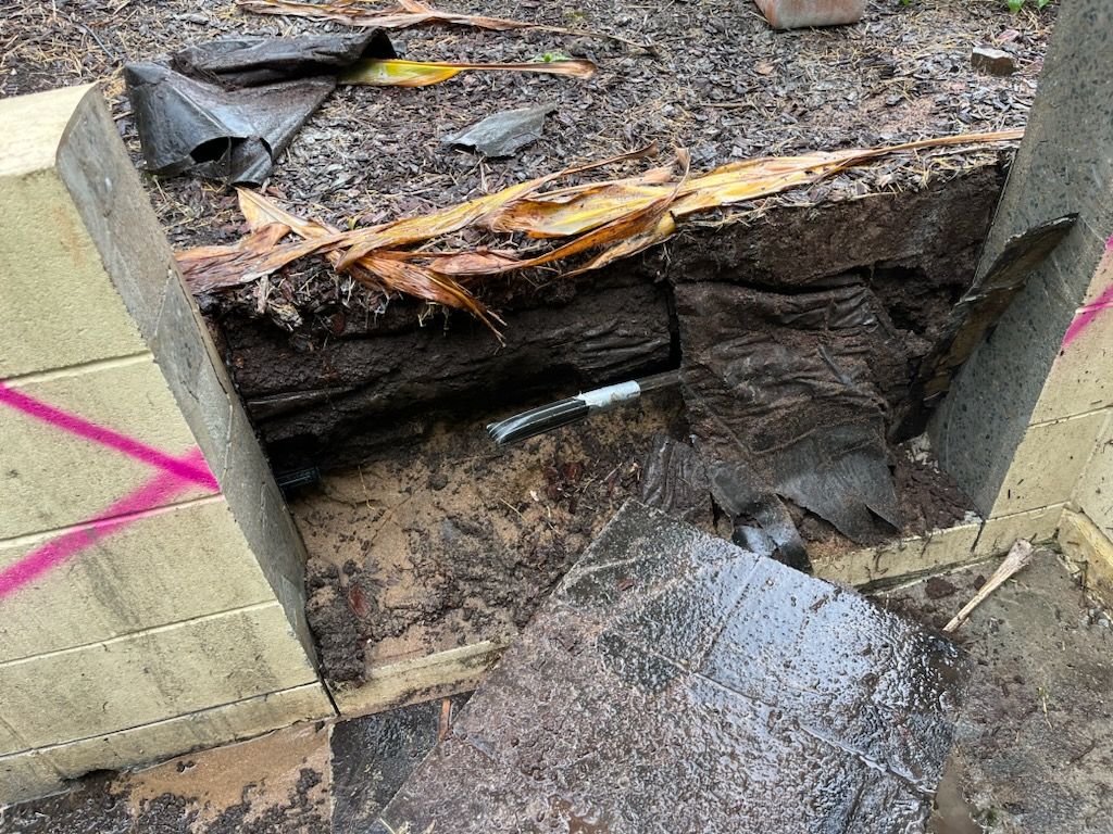 Collapsed roadside culvert with exposed earth, broken concrete, and water rushing through debris — Ablecut Concrete Cutting & Coring In East Mackay, QLD