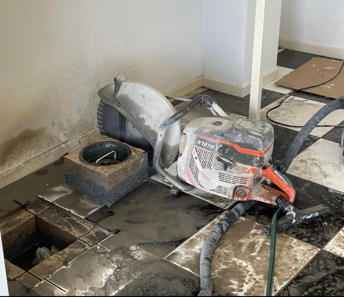 Damaged concrete floor with a power saw and debris in a renovation workspace — Ablecut Concrete Cutting & Coring In East Mackay, QLD