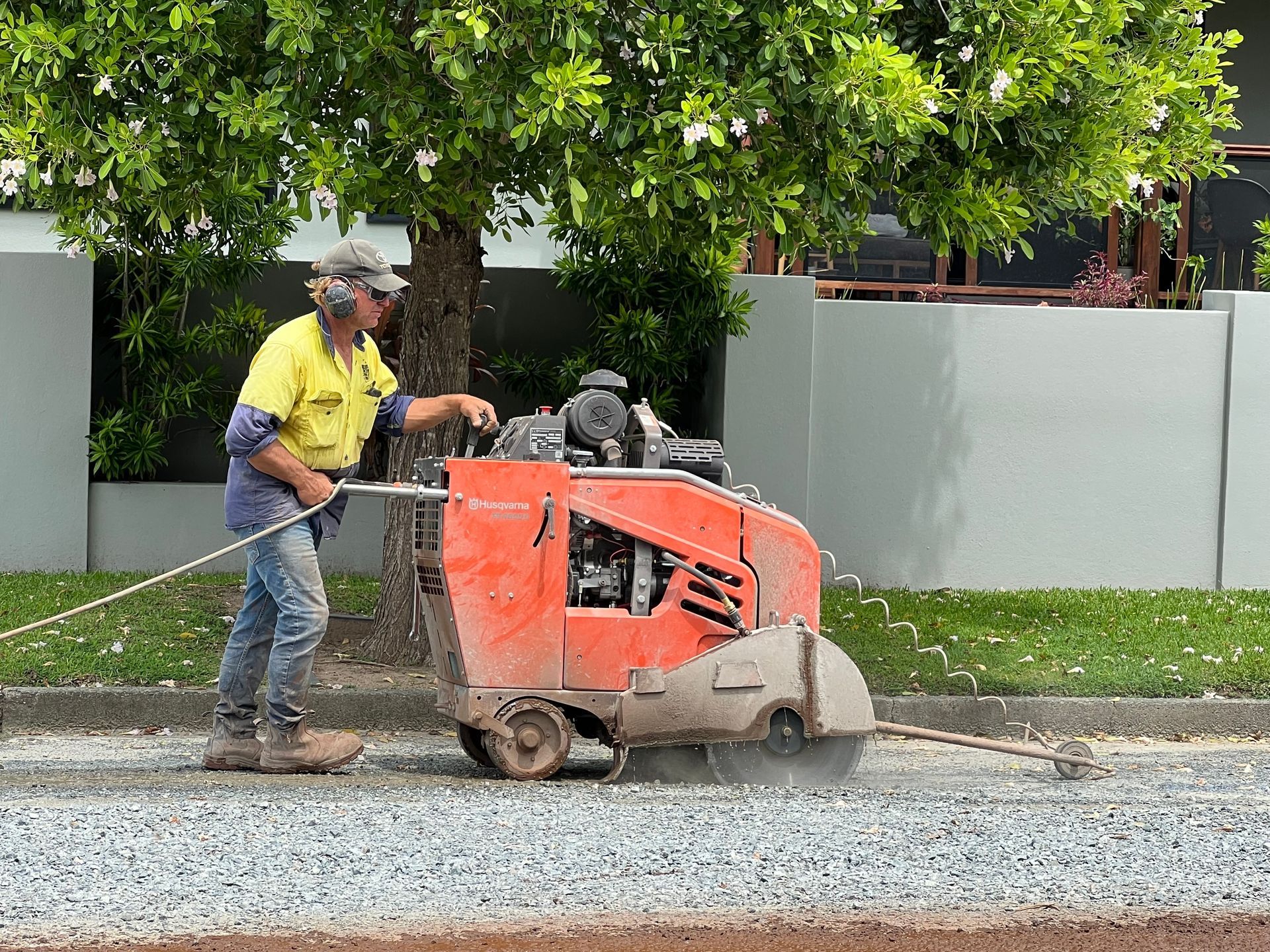 Man operating an orange concrete saw on a gravel road — Ablecut Concrete Cutting & Coring In East Mackay, QLD