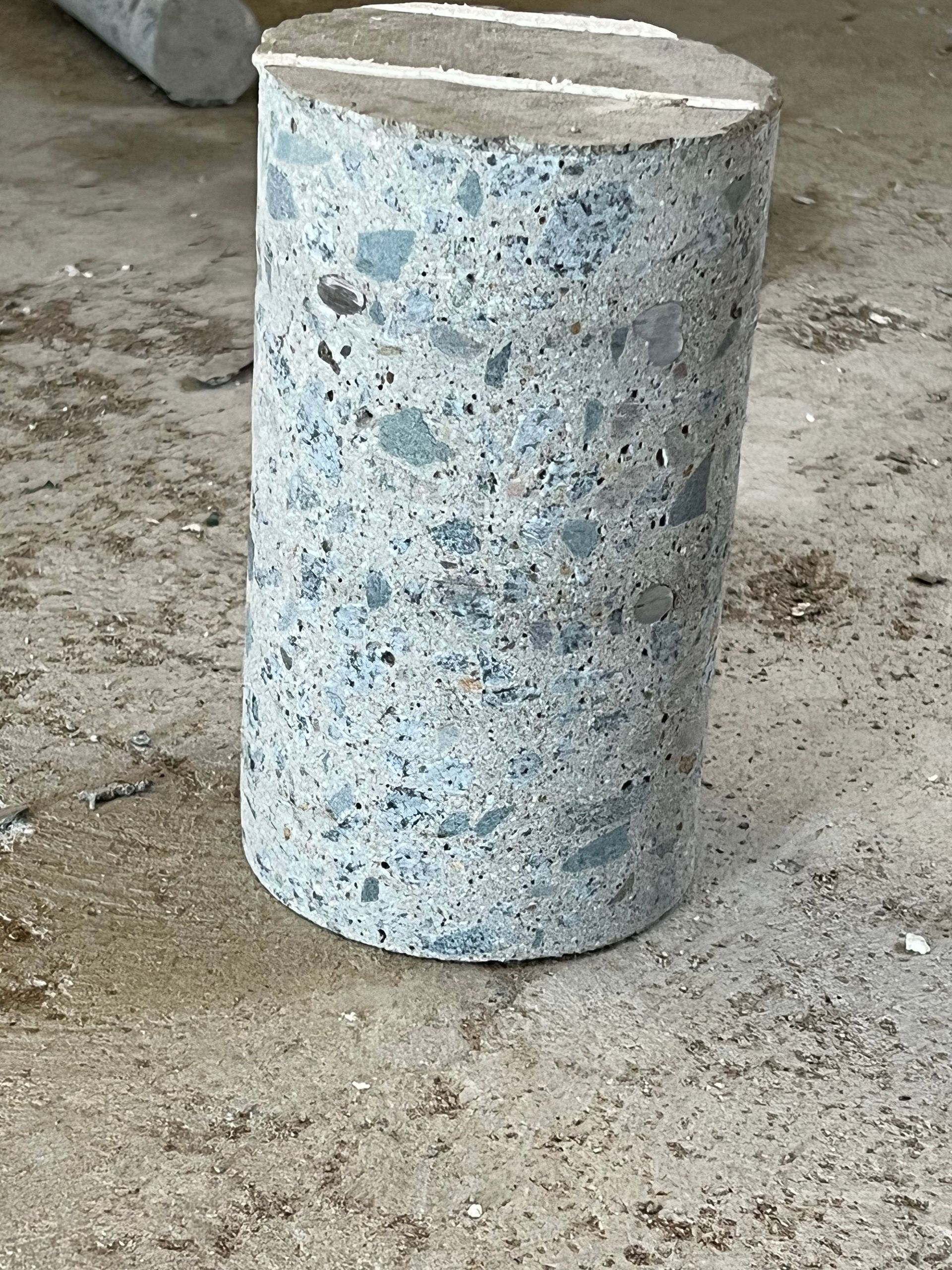 White-speckled concrete cylinder on a rough concrete floor — Ablecut Concrete Cutting & Coring In East Mackay, QLD