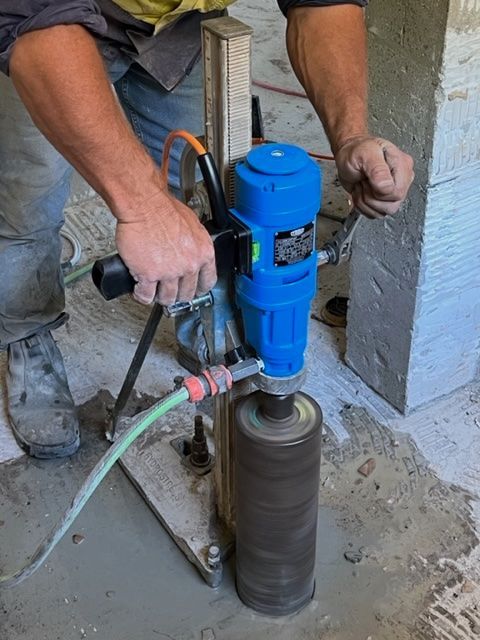 Person Using a Blue Core Drilling Machine on Concrete — Ablecut Concrete Cutting & Coring In Sarina, QLD