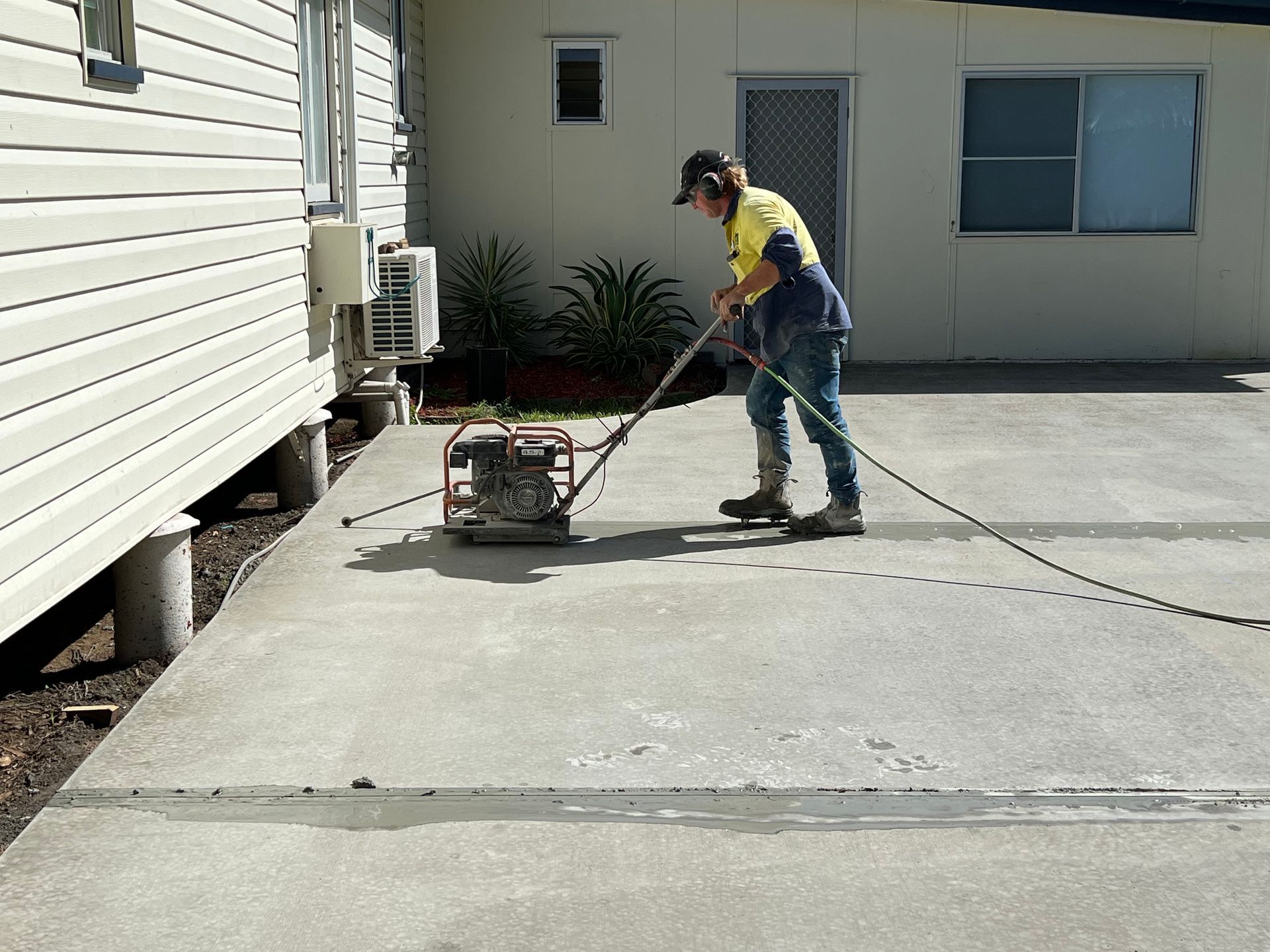 Person Uses a Plate Compactor on Concrete at a Construction Site — Ablecut Concrete Cutting & Coring In East Mackay, QLD