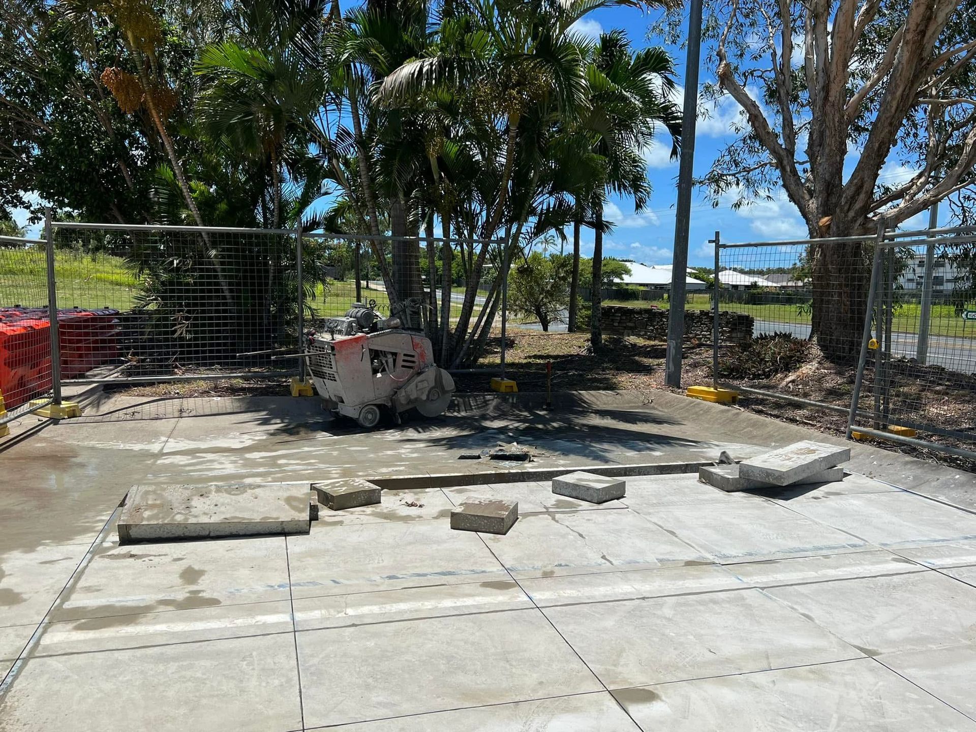 Outdoor concrete patio with scattered slabs, a wire fence, and palm trees near the beach — Ablecut Concrete Cutting & Coring In East Mackay, QLD