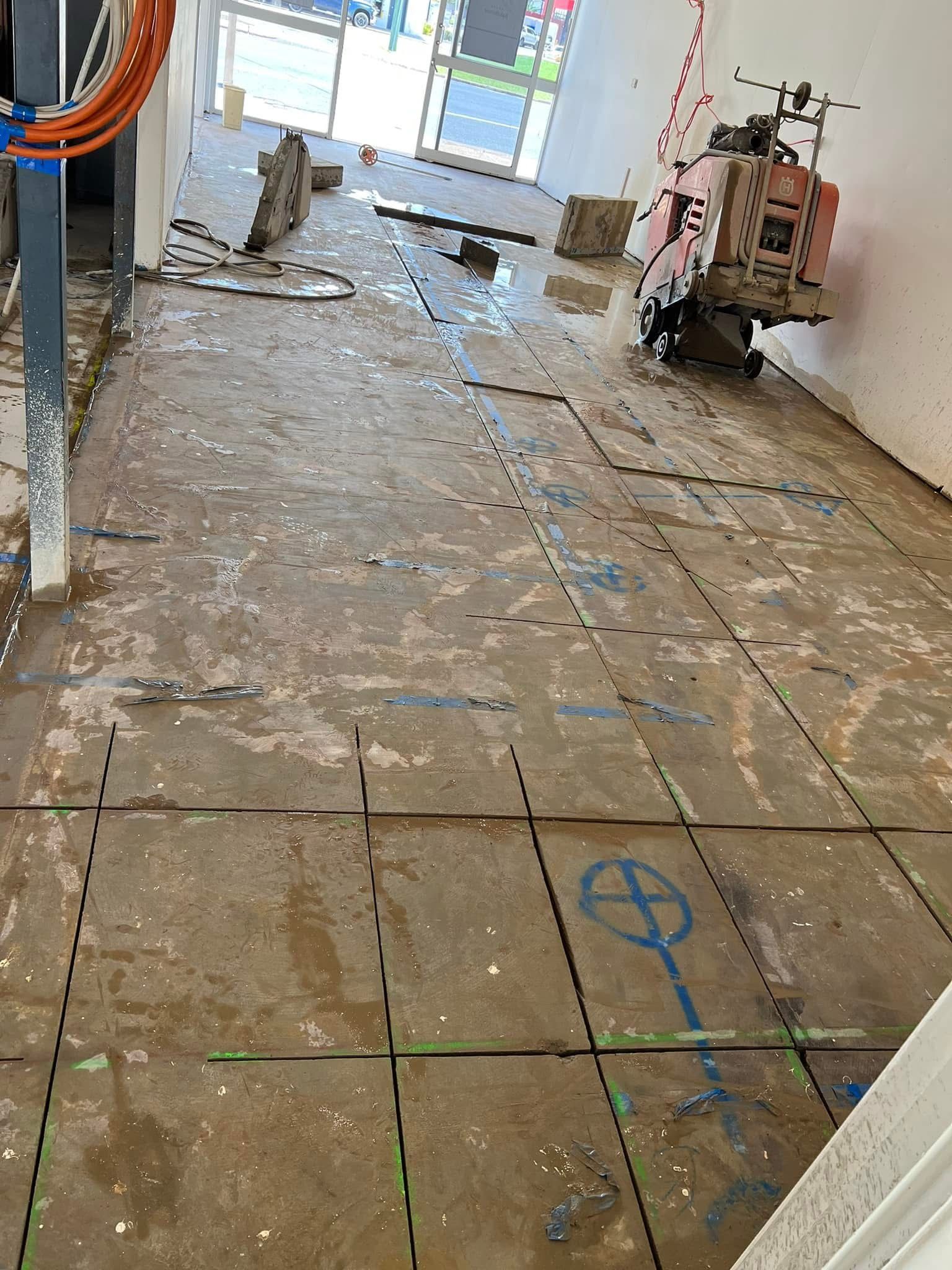 Damaged indoor floor with debris, exposed tiles, and construction tools near a doorway. — Ablecut Concrete Cutting & Coring In East Mackay, QLD