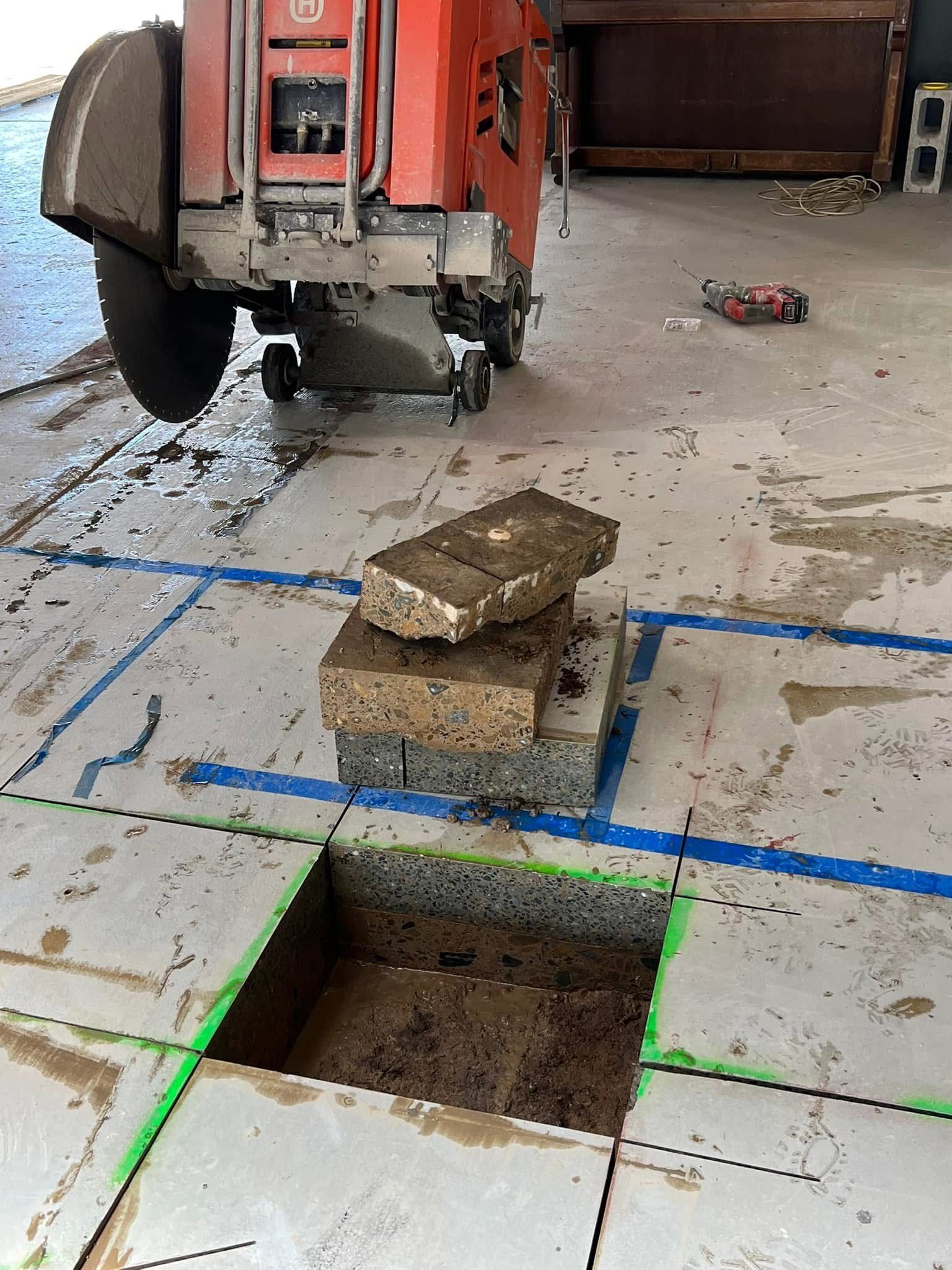 Construction site floor with a square opening, stacked bricks, and a red machine nearby. — Ablecut Concrete Cutting & Coring In East Mackay, QLD